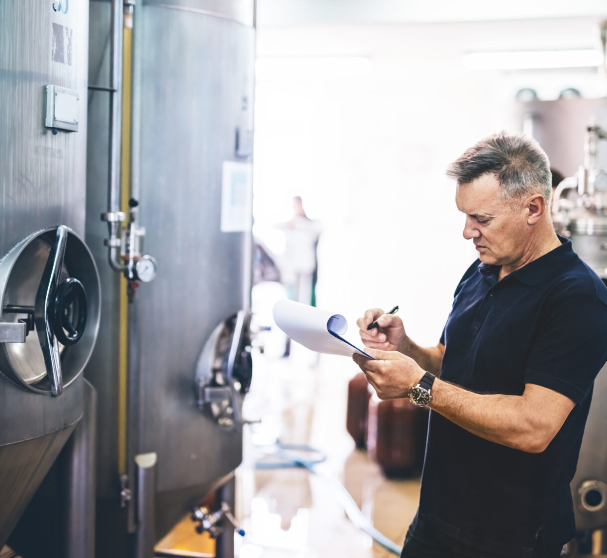 Manager of brewery inspecting equipment producing craft beer