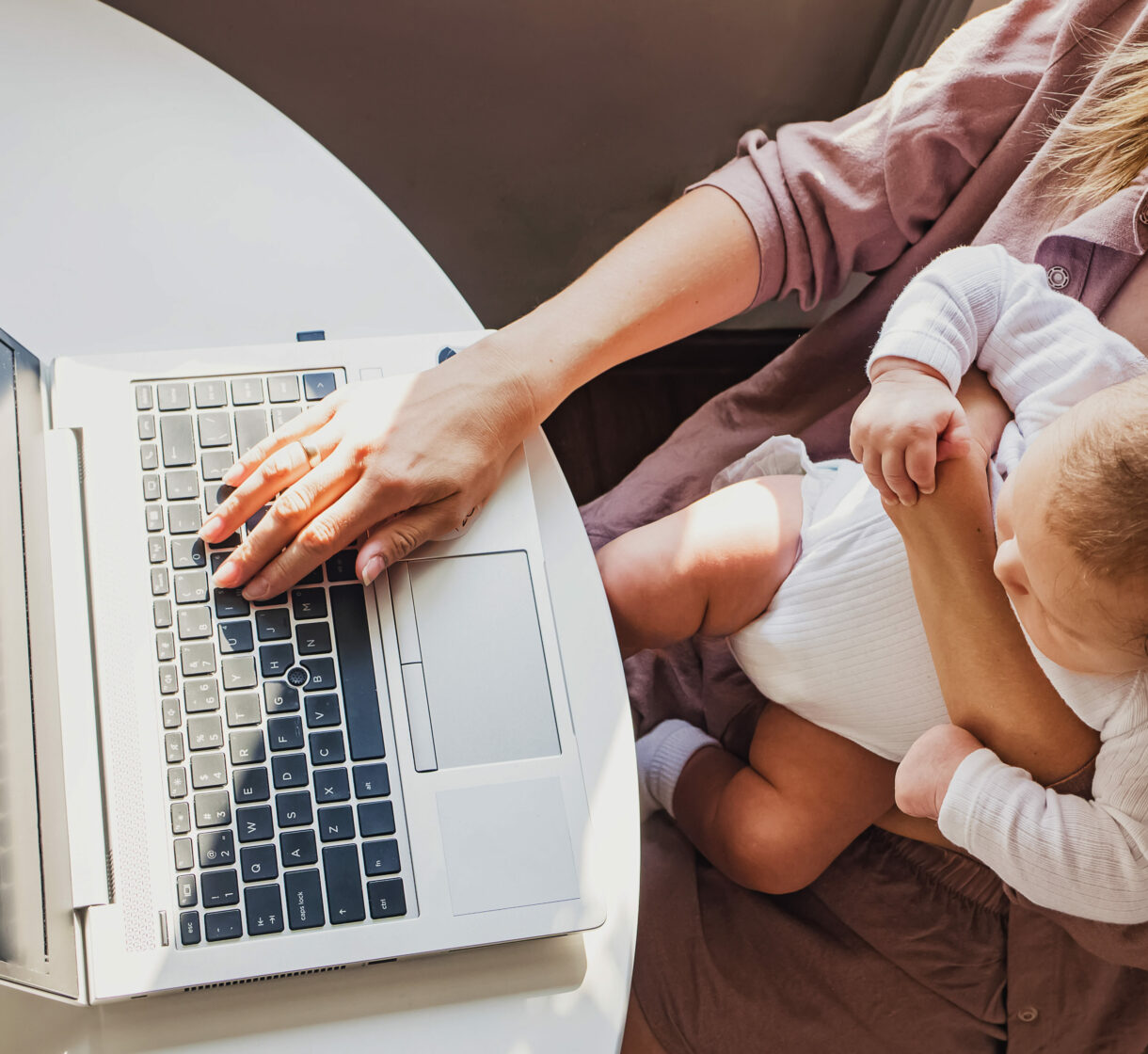 Young mom working on laptop while taking care of her baby