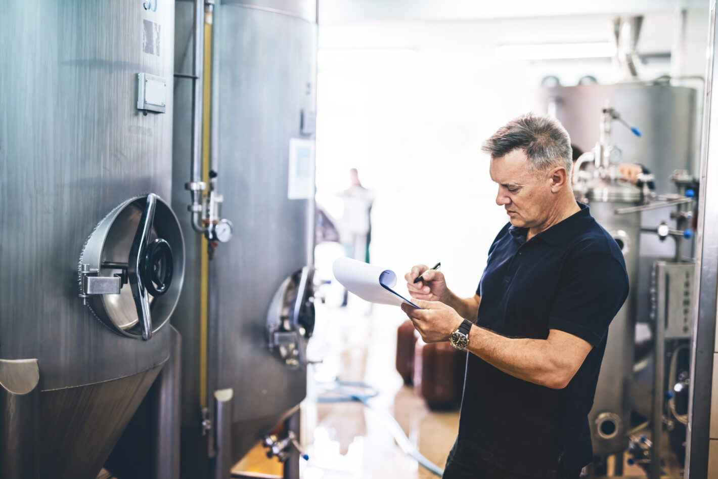 Manager of brewery inspecting equipment producing craft beer